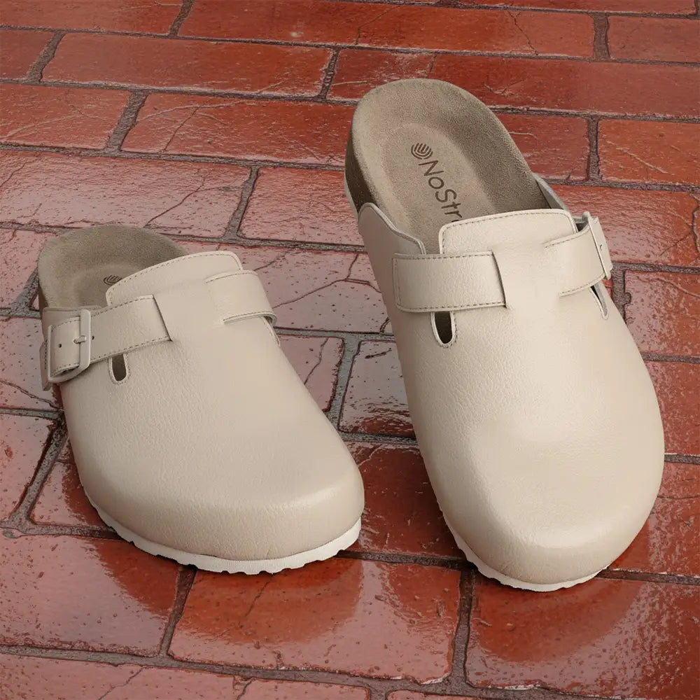 A pair of beige half shoes on a red brick floor