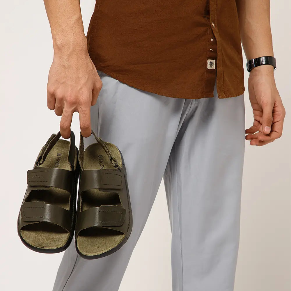 Hand holding the lightweight, premium Olive Green leather sandal with suede insole.