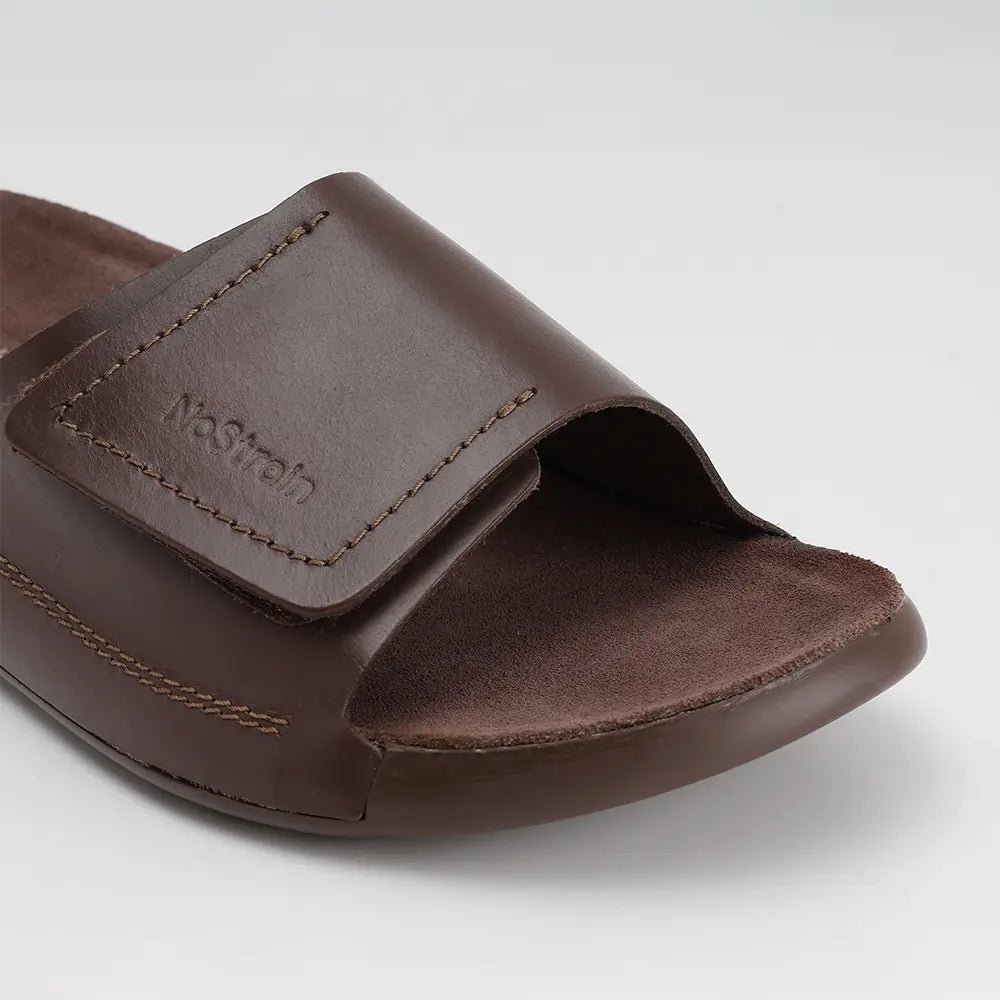 Brown leather sliders for women featuring a broad adjustable strap and durable PU outsole. ISI marked for premium quality, effortless style, and ultimate NoStrain comfort.