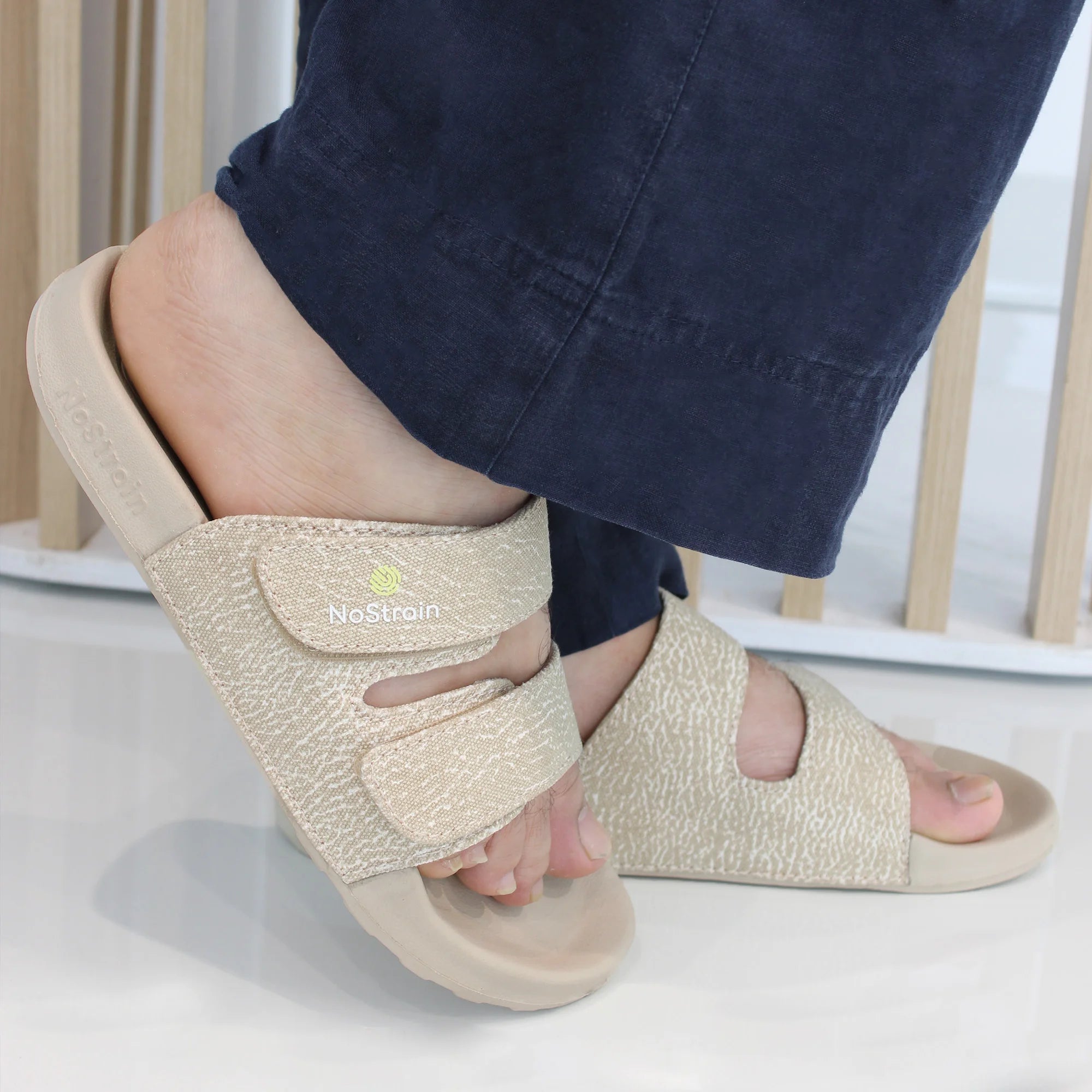 Side view of sandy beige sliders showing wave print on the strap.