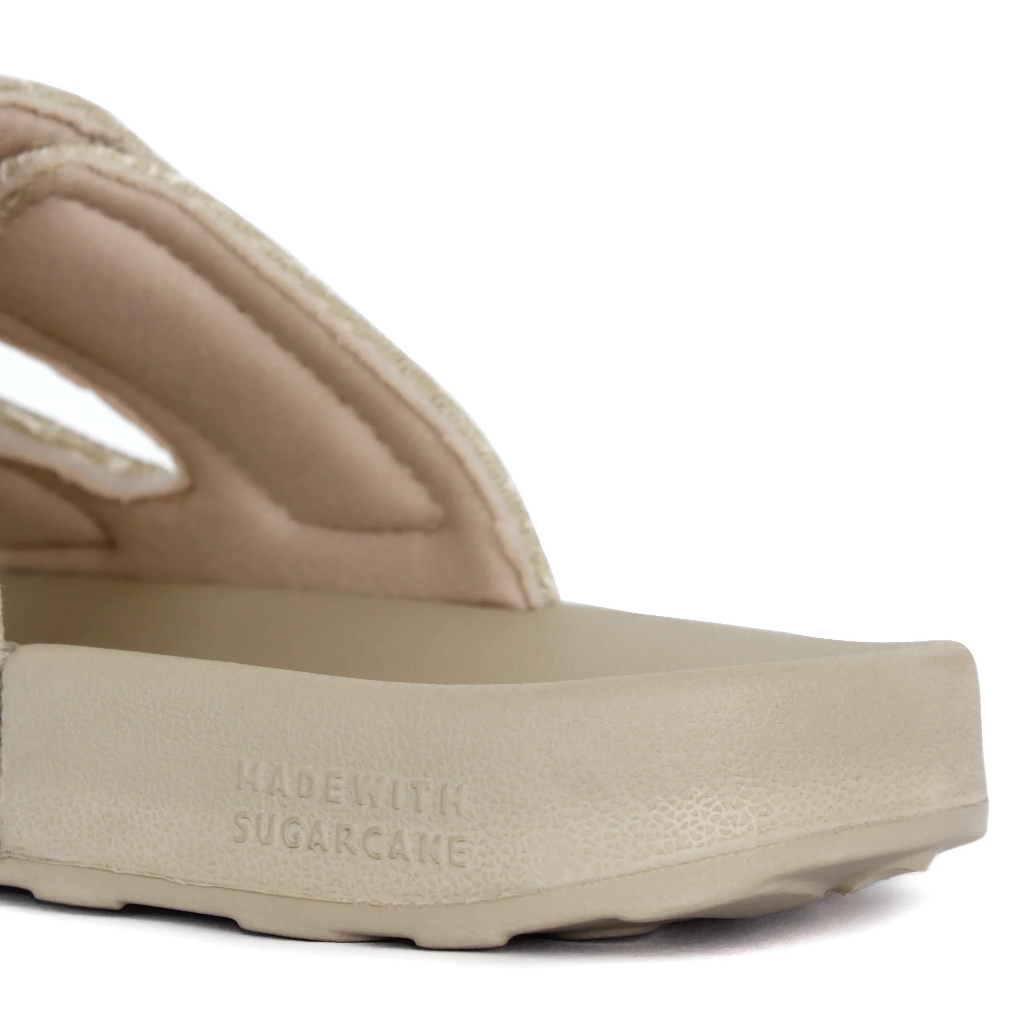 Close-up of the sole branding on the sandy beige sliders.